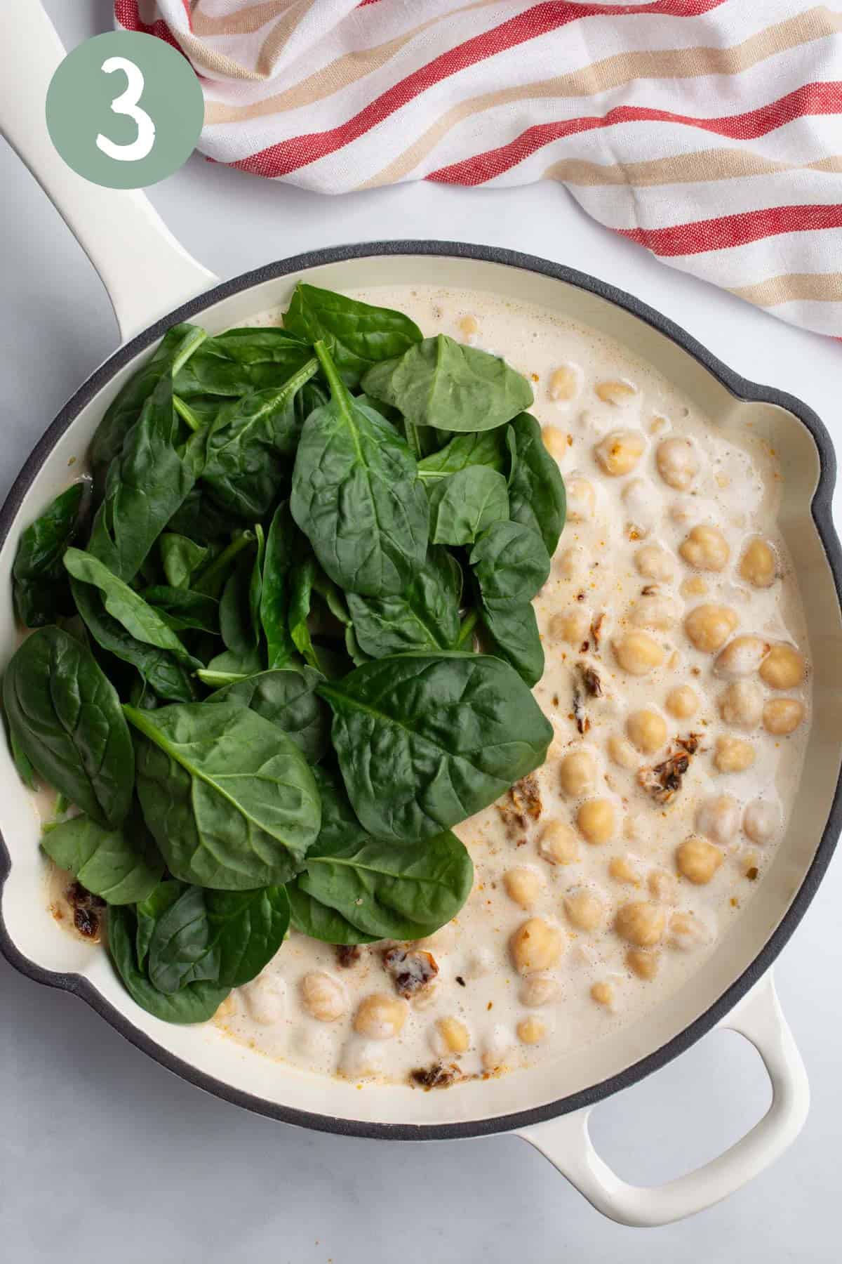 Chickpeas in a cream sauce with fresh spinach on top.