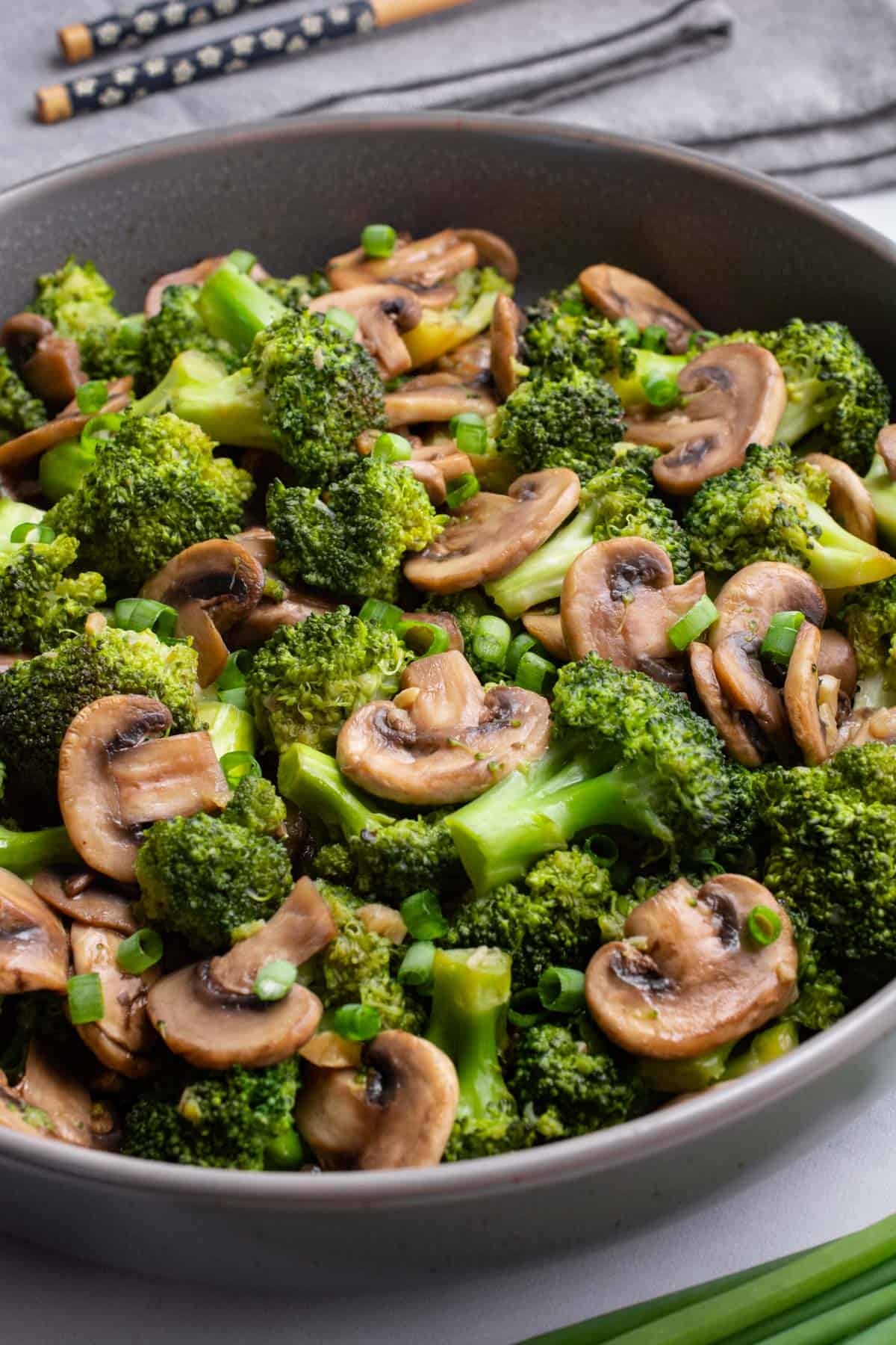 A serving bowl of stir-fried teriyaki mushrooms and broccoli.